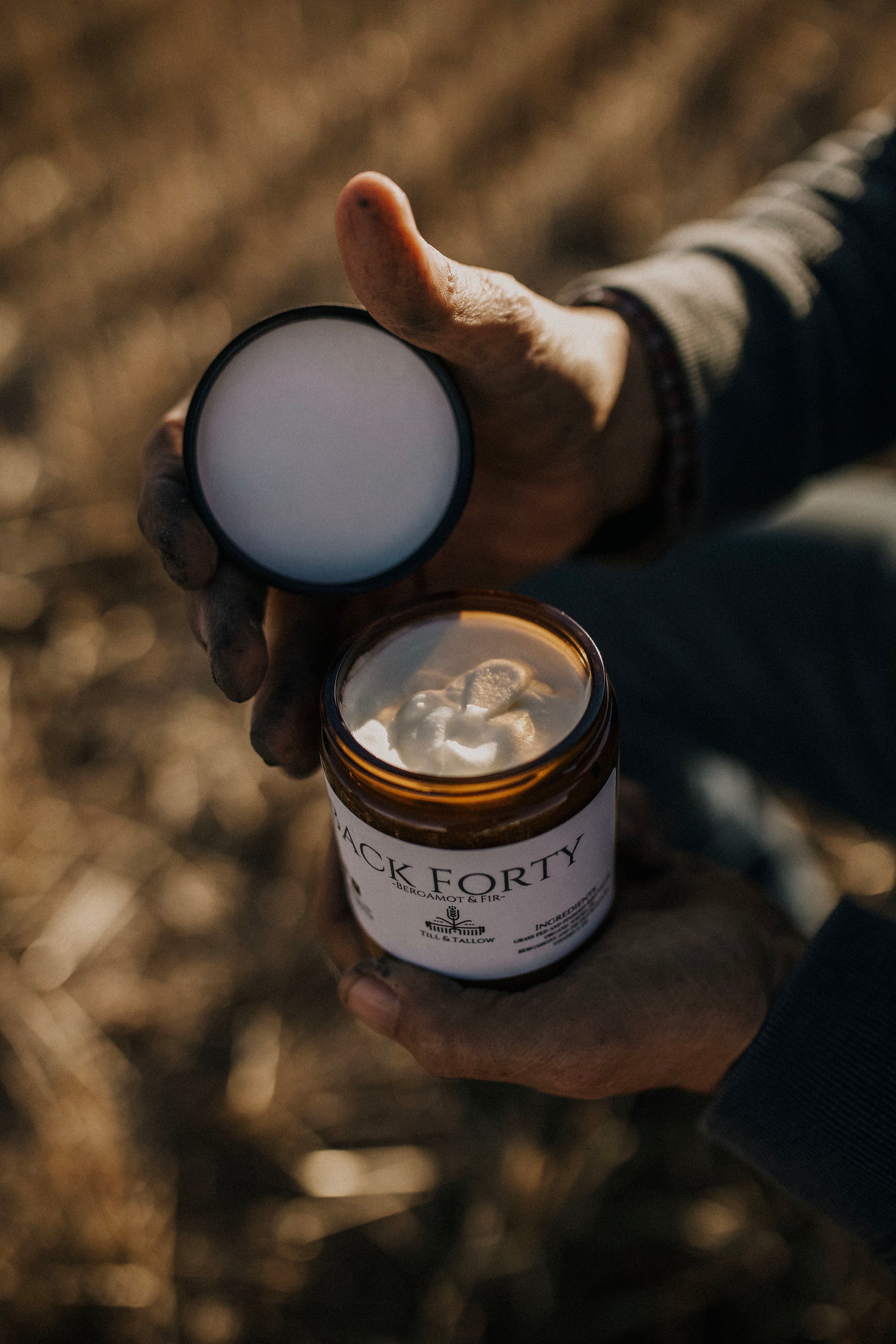 Till & Tallow Back Forty Body Butter open jar in farmers hand, handcrafted in Alberta.