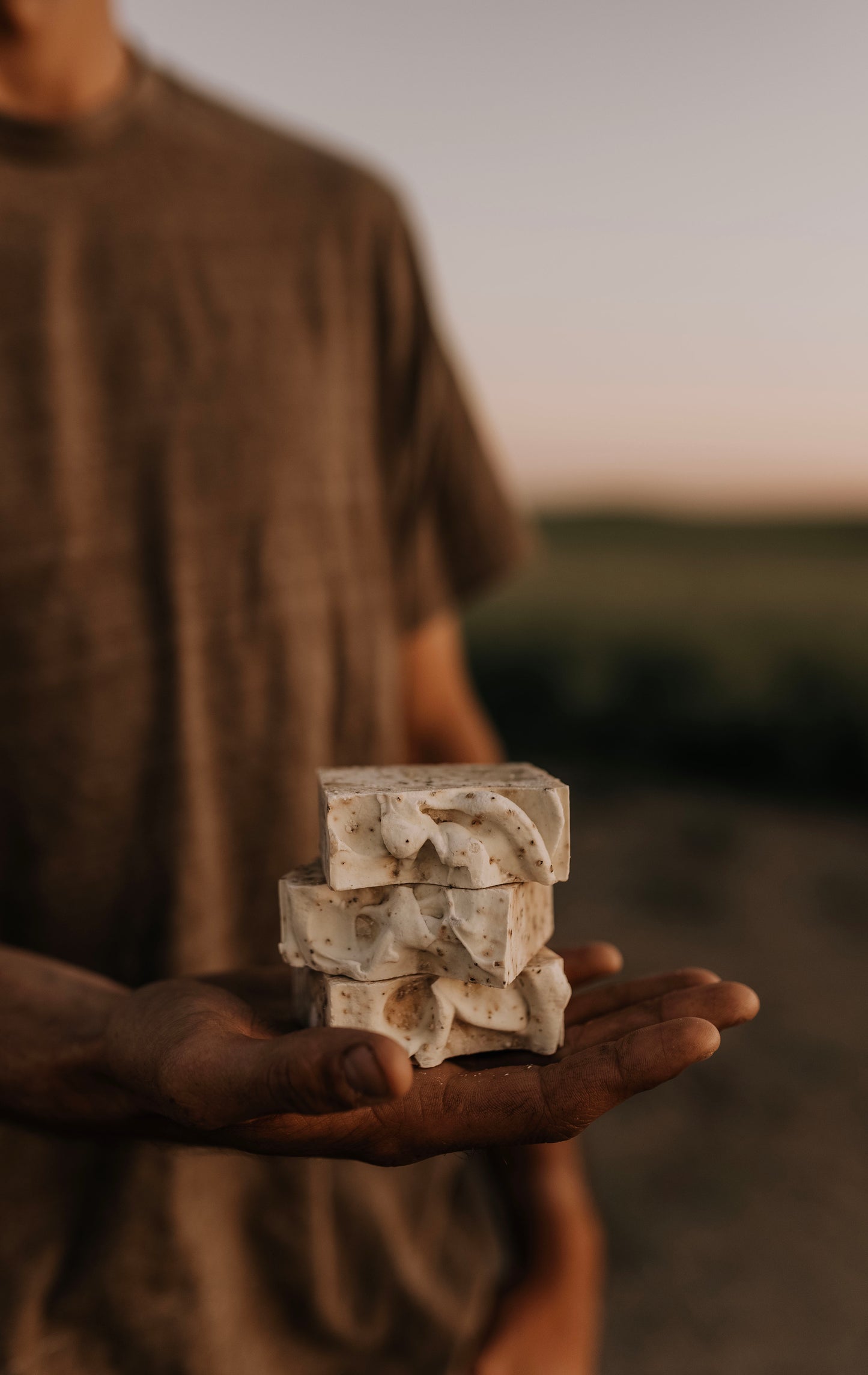 Till and Tallow Bin Bust Soap Degreaser bars held in a person's hand outdoors with a soft, natural background, handcrafted in Alberta.