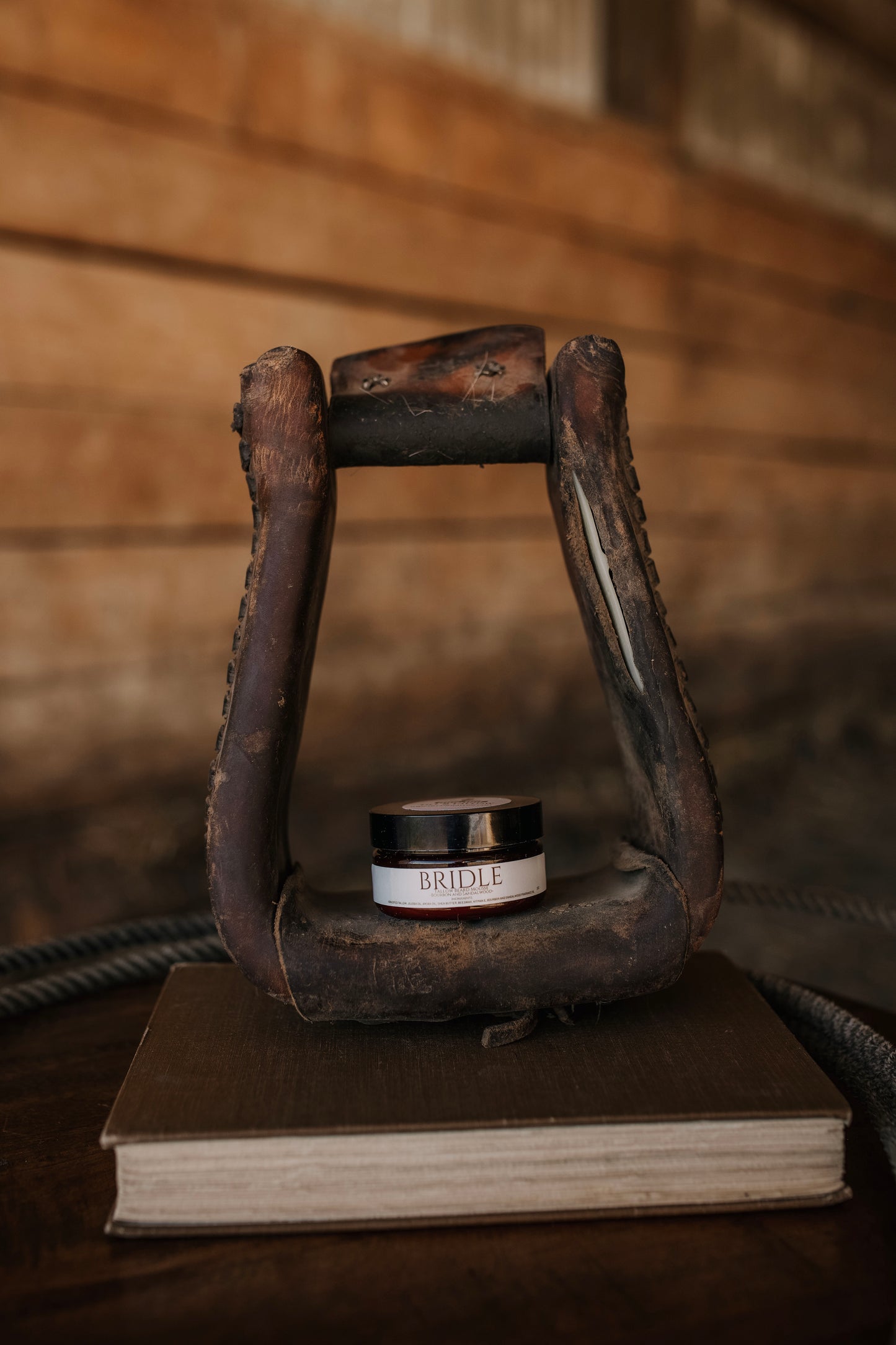Till & Tallow Bridle Beard Mousse in amber jar displayed in a horse stirrup, handcrafted in Alberta