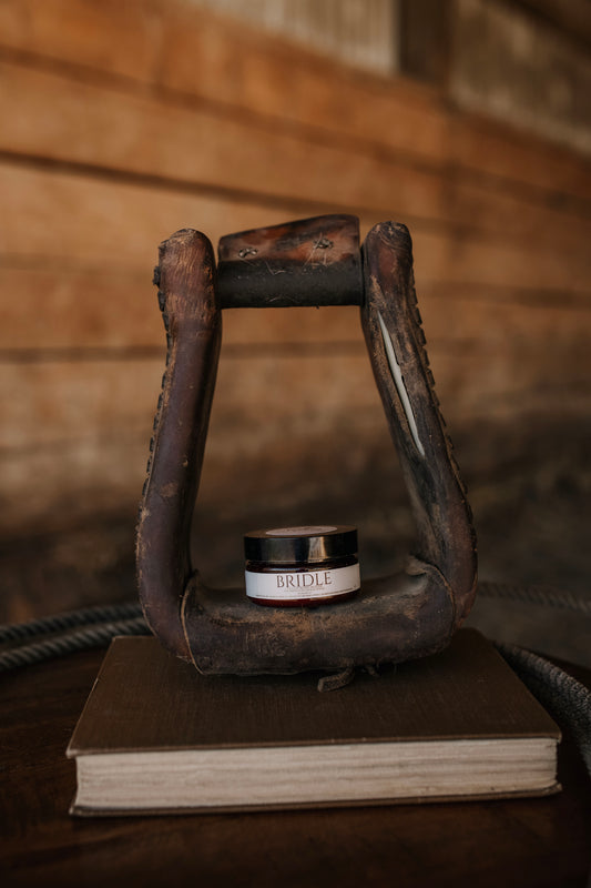 Till & Tallow Bridle Beard Mousse in amber jar displayed in a horse stirrup, handcrafted in Alberta