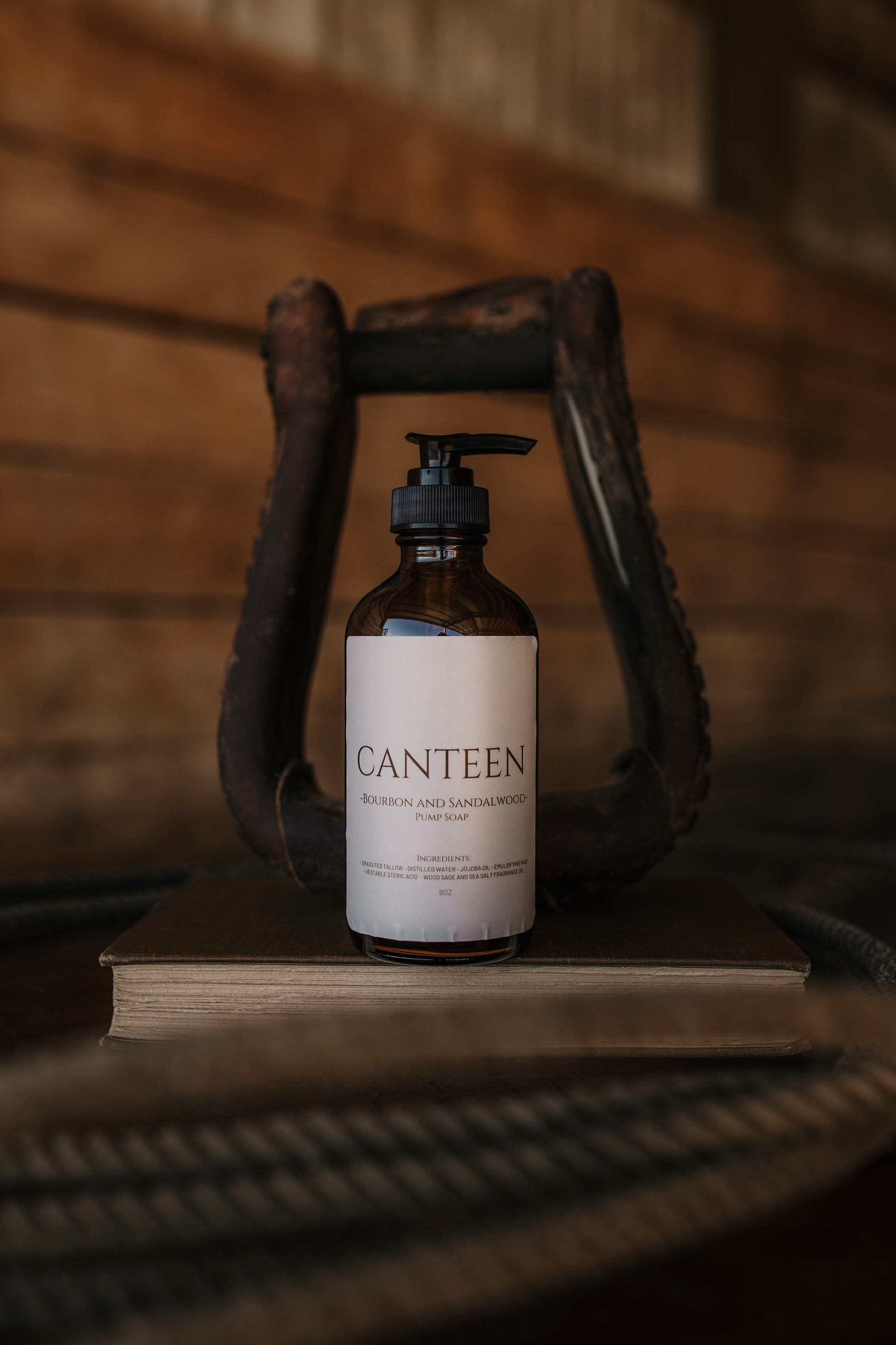 Till & Tallow Canteen Liquid Hand Soap bottle displayed inside a rustic horse stirrup on a wooden surface, handcrafted in Alberta.