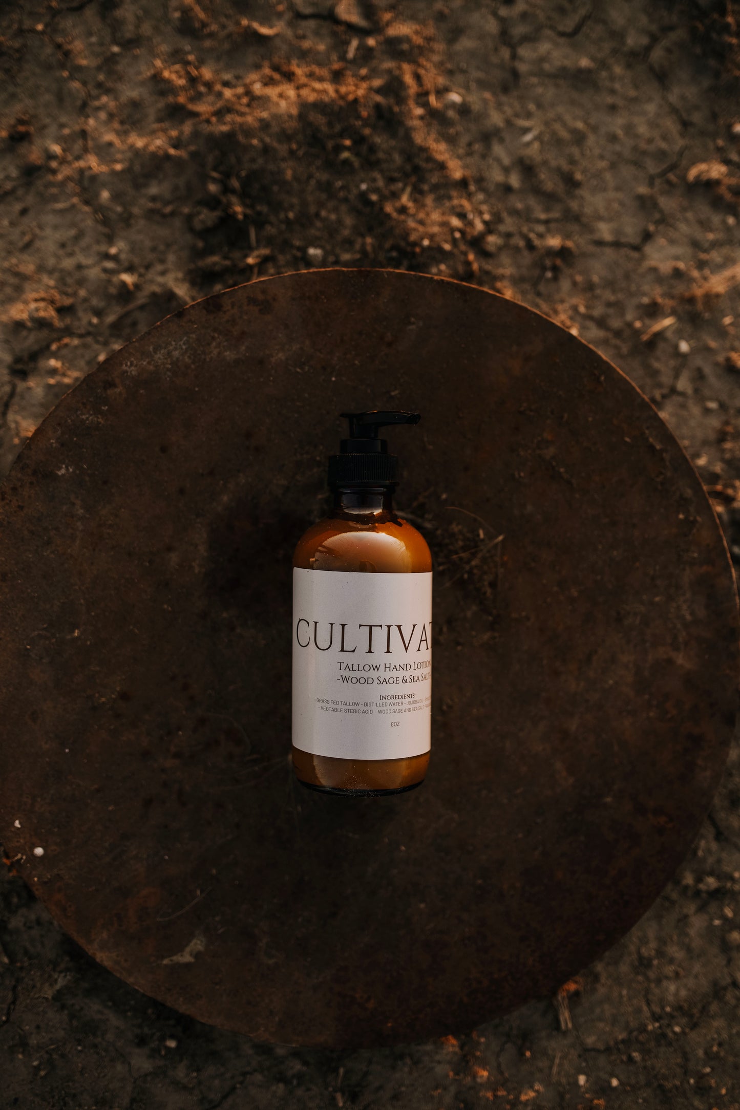 Till & Tallow Cultivated Pump Lotion on Metal disk in the dirt, handcrafted in Alberta.