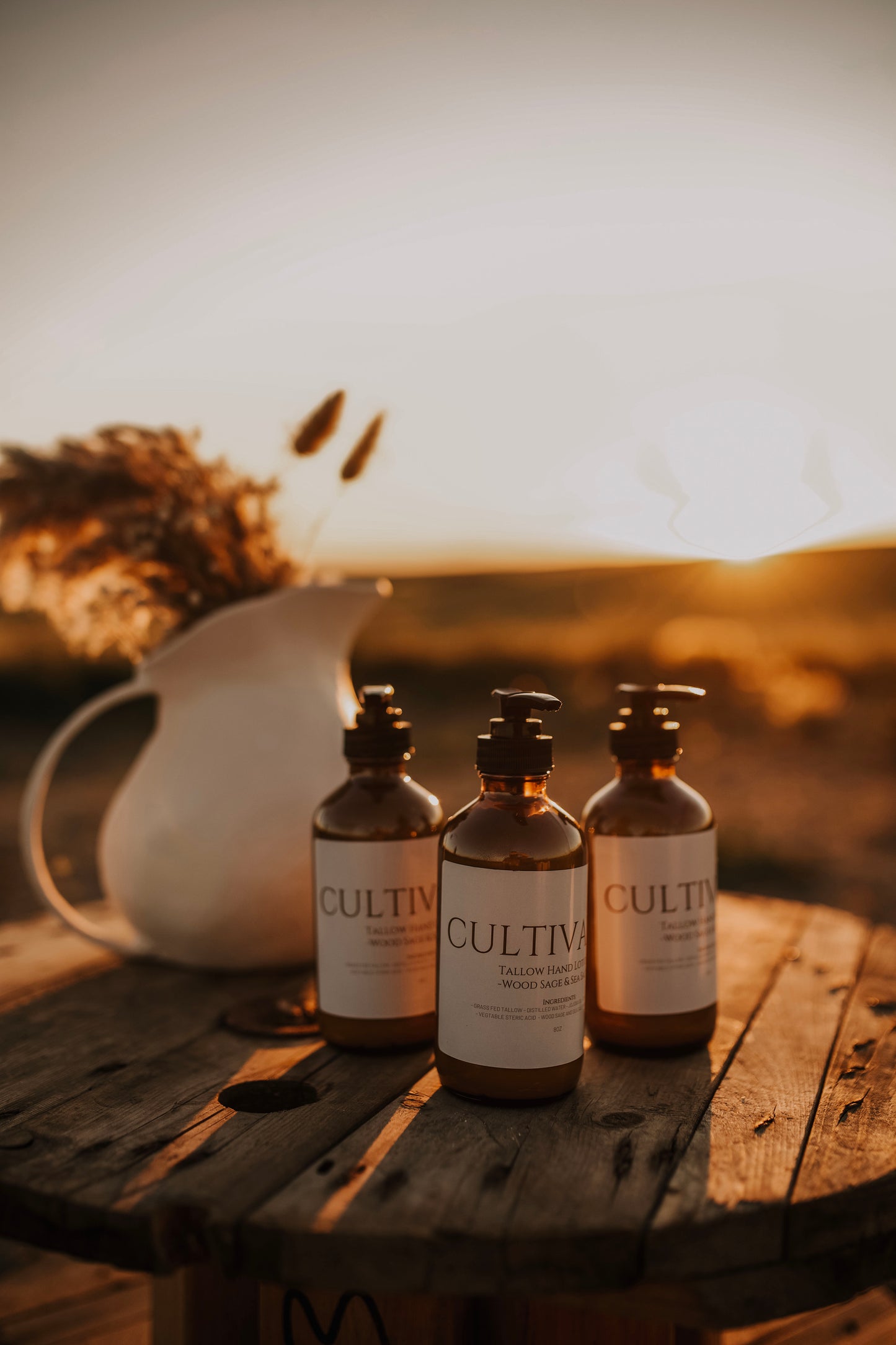 Till & Tallow Cultivated Pump Lotion bottles on wooden table outdoors, handcrafted in Alberta.