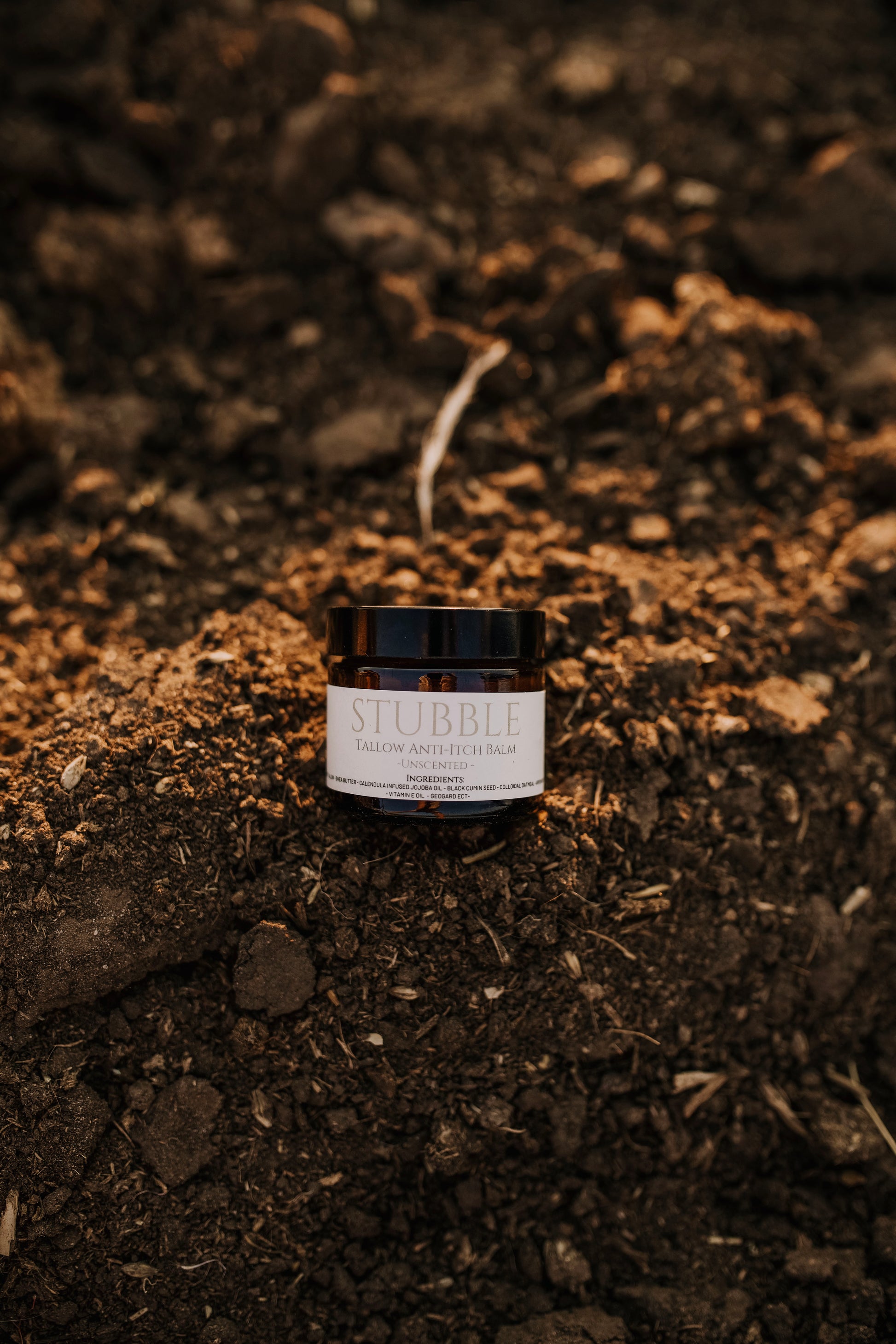 Till & Tallow Stubble Anti-Itch Balm jar resting on an earthy textured surface, natural tallow-based skincare, handcrafted in Alberta.