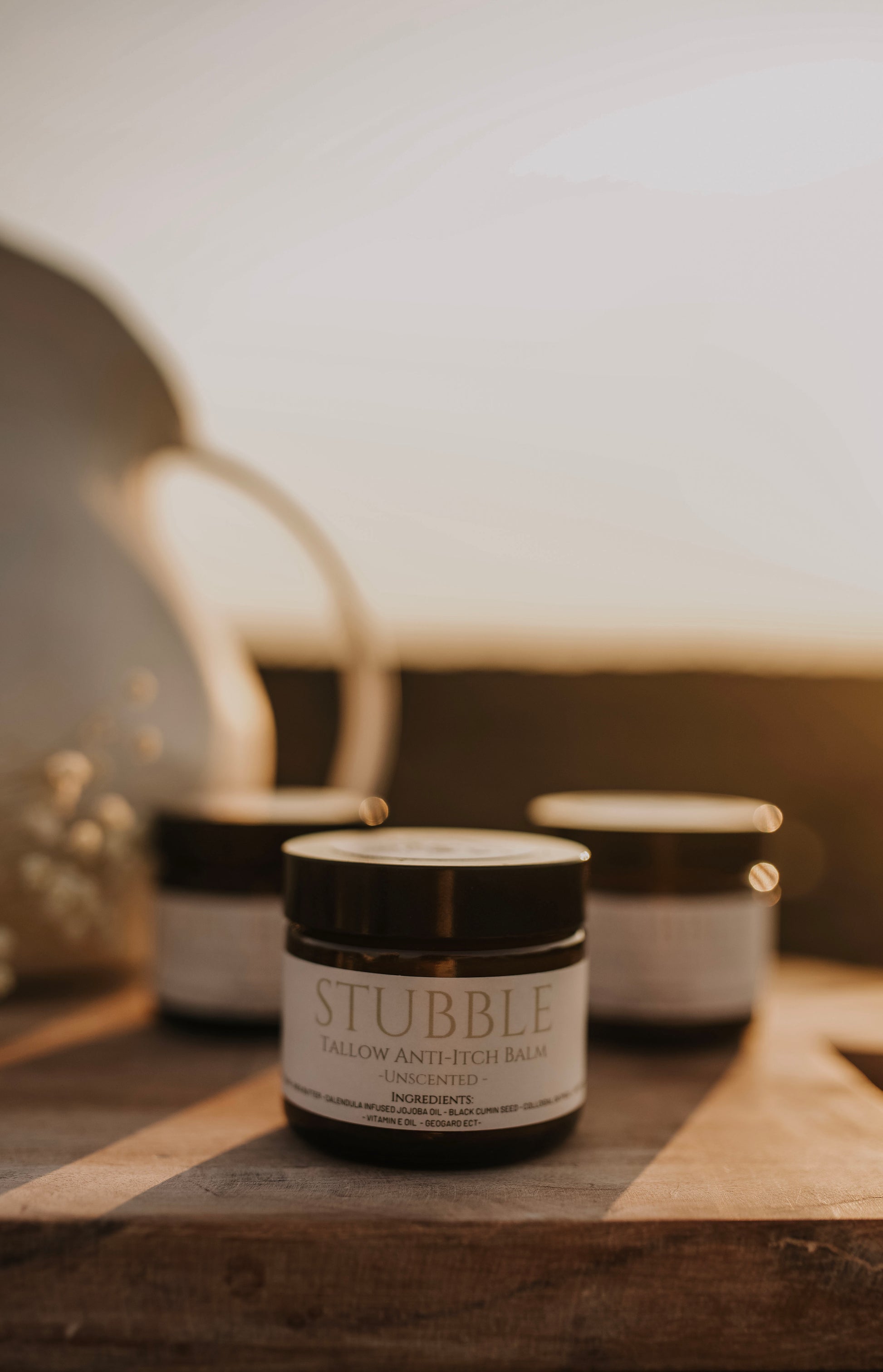 Till & Tallow Stubble Anti Itch Balm jar on a wooden surface with warm morning light, handcrafted in Alberta